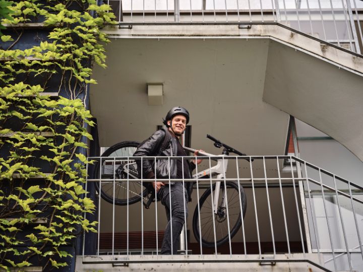 JobRadler mit Fahrrad nimmt grinsend die Treppe